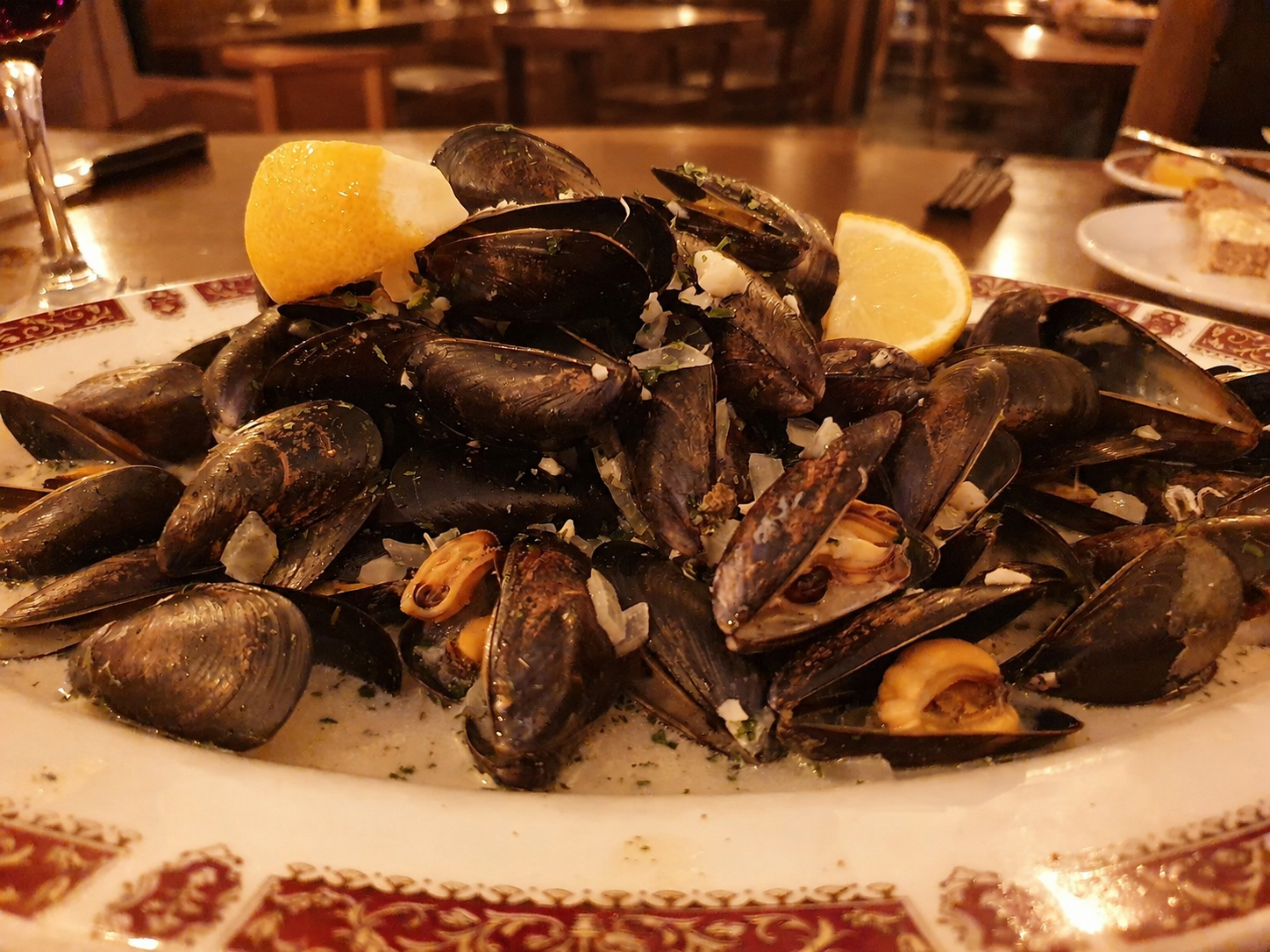 A platter of mussels with lemon wedges